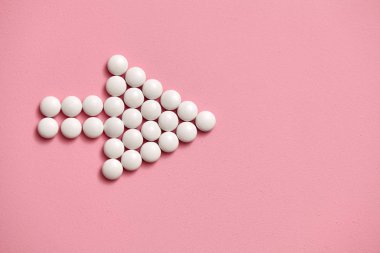 Ok işareti beyaz, pembe bir arka plan üzerinde tablet yuvarlak ile kaplı