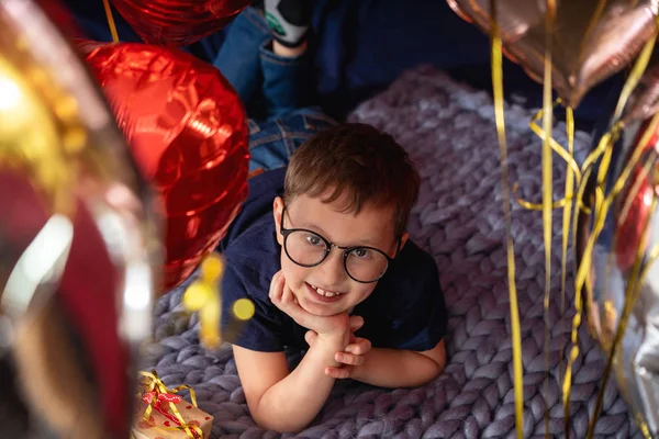Niño con gafas está soñando mientras está acostado en la cama, un celebrati —  Fotos de Stock