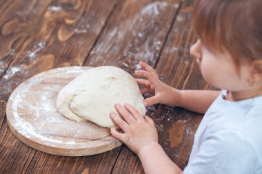 bir çocuğun elinde hamur, ahşap bir masa. SH alınan