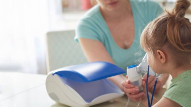 bir kadın bir çocuk evde inhalasyon yapıyor. nebulize getiriyor