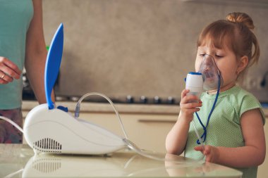 bir kadın bir çocuk evde inhalasyon yapıyor. nebulize getiriyor