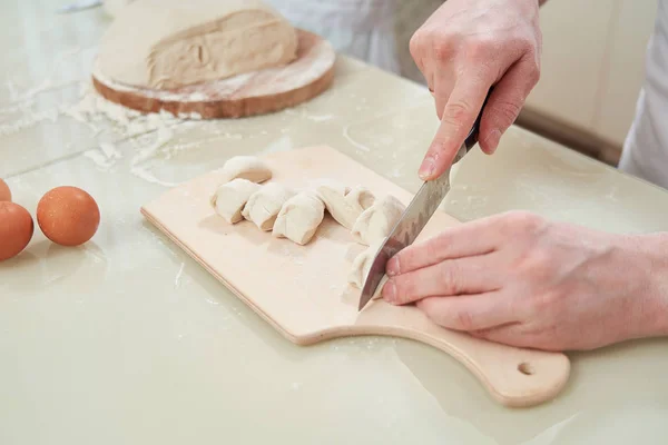 Чоловік шеф-кухар розрізає тісто на шматки — стокове фото