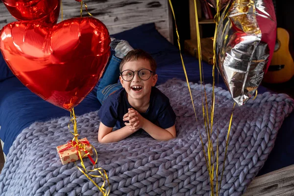 Niño feliz con gafas riendo acostado en la cama, decora de vacaciones —  Fotos de Stock