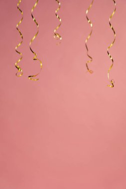 Kıvrık kurdela mercan pembe bir arka plan üzerinde asılı parti kümesi.