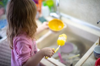 Çocuk bulaşıkları yıkar, mutfakta yeni yardım alma deneyimi