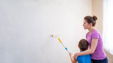 Annesiyle birlikte bir çocuk duvarları boyar. p'de bitirme işi