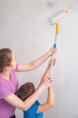 Annesiyle birlikte bir çocuk duvarları boyar. p'de bitirme işi