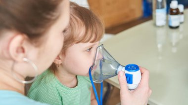 kadın bir çocuk evde inhalasyon yapar. Nebulizatör getiriyor 