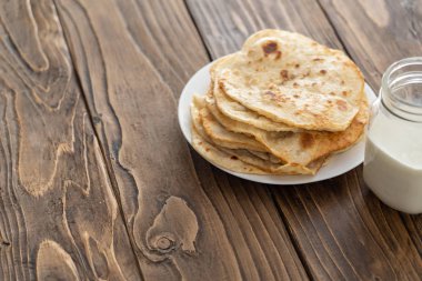 bir fincan süt ve bir tabak kızarmış Mısır ekmeği ahşap bir metin üzerinde