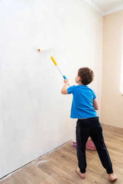 child rolls the roller in the paint on the wall. finishing work