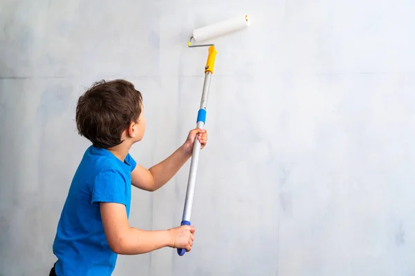 child rolls the roller in the paint on the wall. finishing work