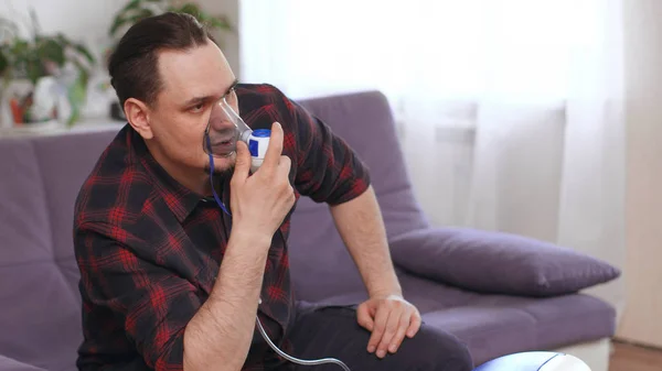 Portrait Of Young Man Inhaling Through Inhaler Mask. self-treatm