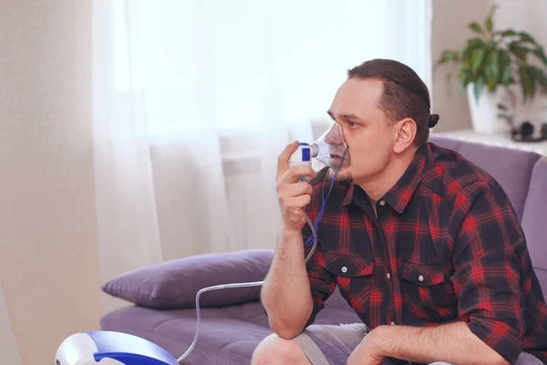 Portrait Of Young Man Inhaling Through Inhaler Mask. self-treatm