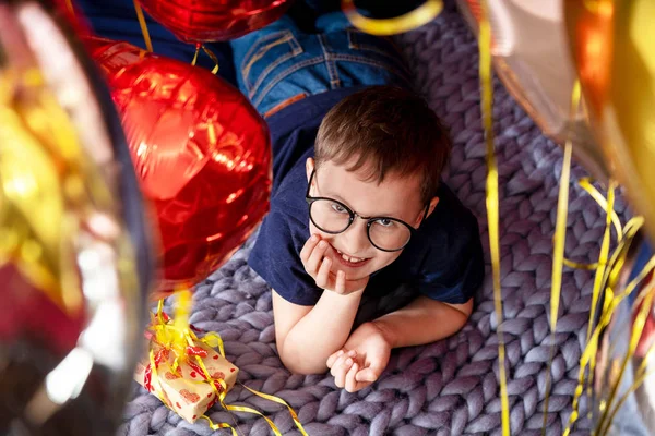 Niño feliz con gafas riendo acostado en la cama, decora de vacaciones —  Fotos de Stock