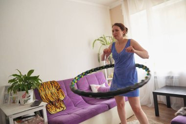 a woman turns a hula Hoop at home. self-training with a Hoop. clipart