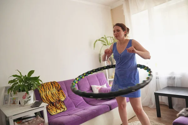 Una donna gira un hula Hoop a casa. auto-allenamento con un cerchio . — Foto Stock