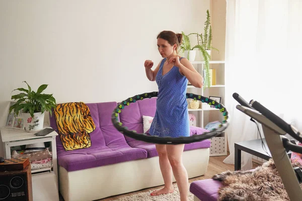 Een vrouw maakt een hula hoop thuis. zelf training met een hoepel. — Stockfoto