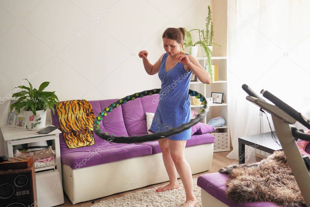 a woman turns a hula Hoop at home. self-training with a Hoop.