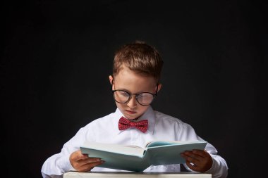 masada oturan bir kitap ile neşeli küçük çocuk. mutlu bir chil