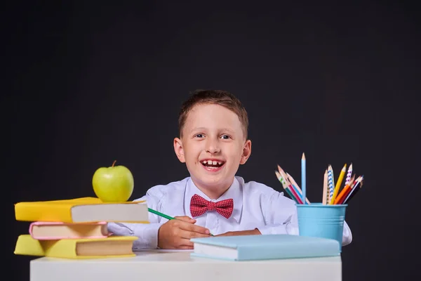 Gioioso bambino seduto su uno sfondo nero su un tavolo con — Foto Stock