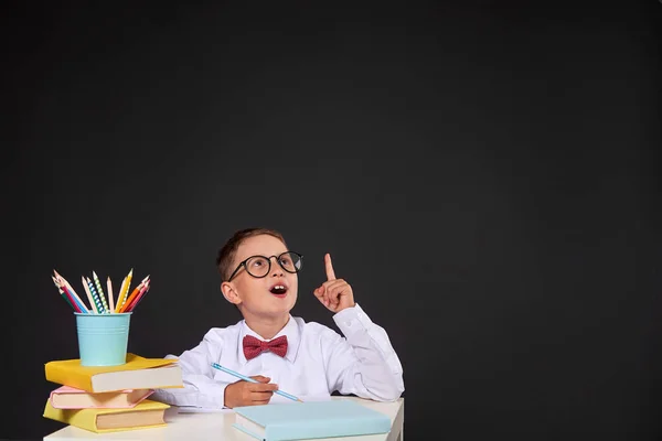 Gioioso bambino seduto su uno sfondo nero a un tavolo con — Foto Stock