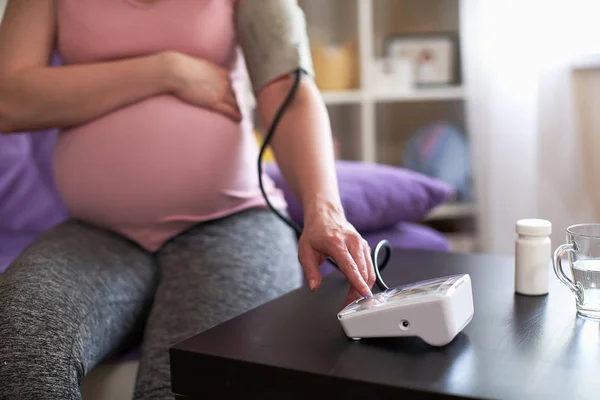 Una donna misura la pressione sanguigna con un manometro elettronico — Foto Stock