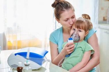 kadın bir çocuk evde inhalasyon yapar. Nebulizatör getiriyor 