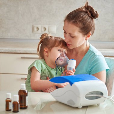 kadın bir çocuk evde inhalasyon yapar. Nebulizatör getiriyor 