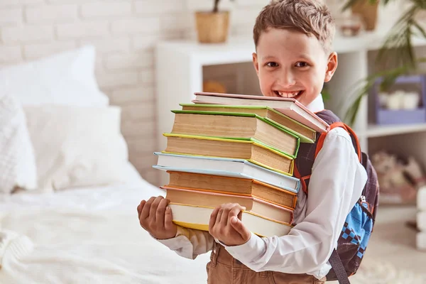 Het kind houdt een stapel studieboeken — Stockfoto