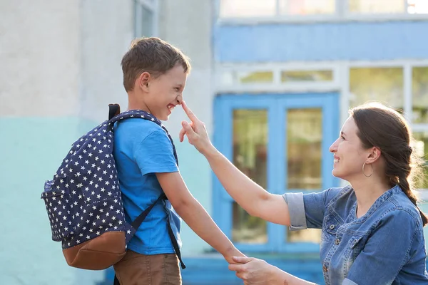 Moeder begeleidt het kind naar school. moeder moedigt student een — Stockfoto