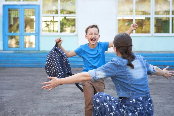 Mamá conoce a su hijo de la escuela primaria. niño alegre se encuentra con — Foto de Stock