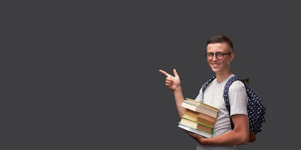 Χαρούμενος έφηβος μαθητής χαμογελά κρατώντας ένα βιβλίο στο χέρι του και p — Φωτογραφία Αρχείου