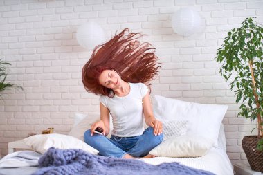 yatakta kulaklıkla müzik dinleyen kız. kızıl saçlı sen