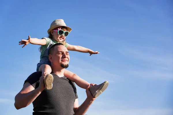 Батько і дочка на плечах щасливо радіють. тато тримає брехню — стокове фото