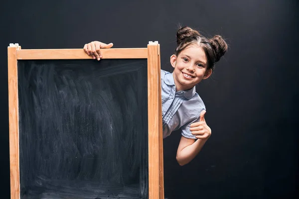 Ребенок показывает знак одобрения стоя на школьном совете . — стоковое фото