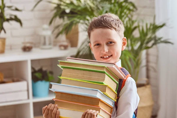 Het kind houdt een stapel studieboeken — Stockfoto