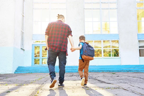 Возвращайся в школу. Счастливые отец и сын ходят в начальную школу . — стоковое фото