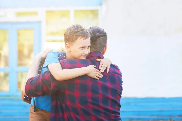 Возвращайся в школу. Счастливые отец и сын обнимаются перед телевизором — стоковое фото