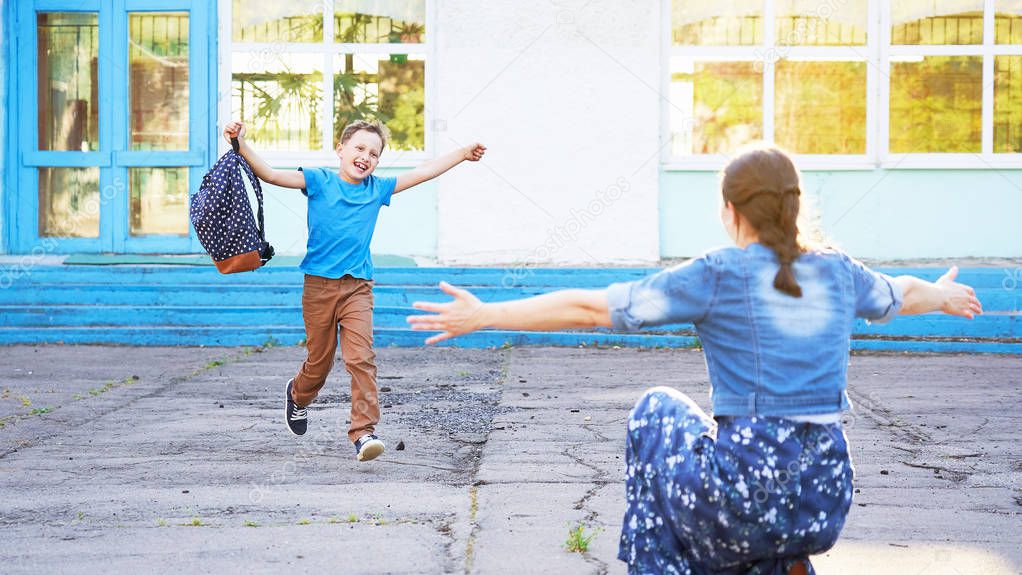 mom meets her son from elementary school. joyful child runs into