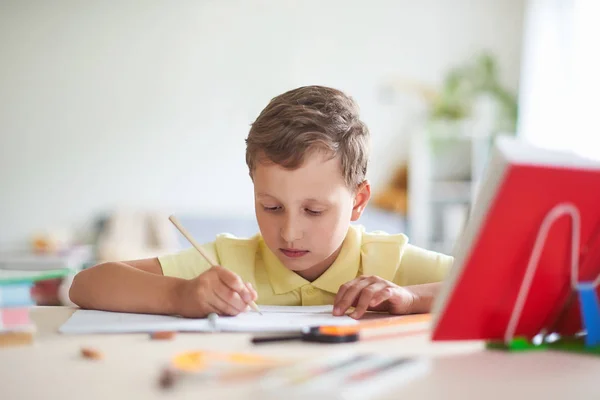 El chico hace su tarea en casa. niño feliz en la mesa con —  Fotos de Stock