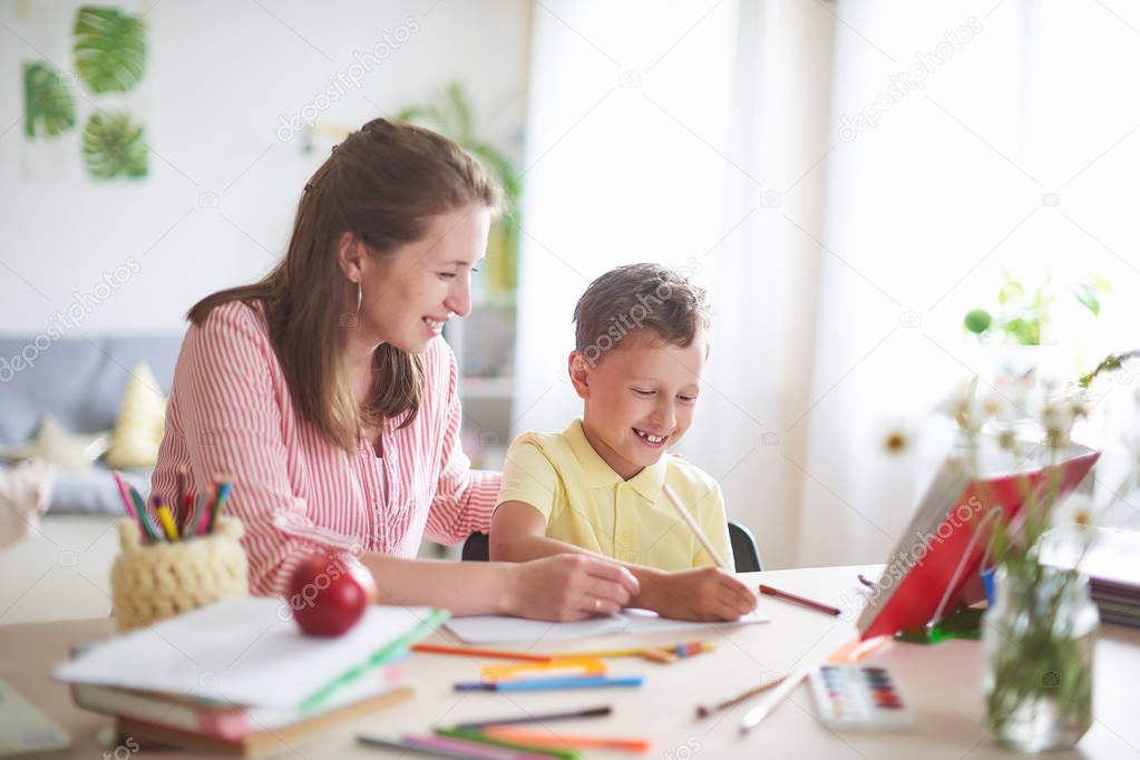 mother helps son to do lessons. home schooling, home lessons. th