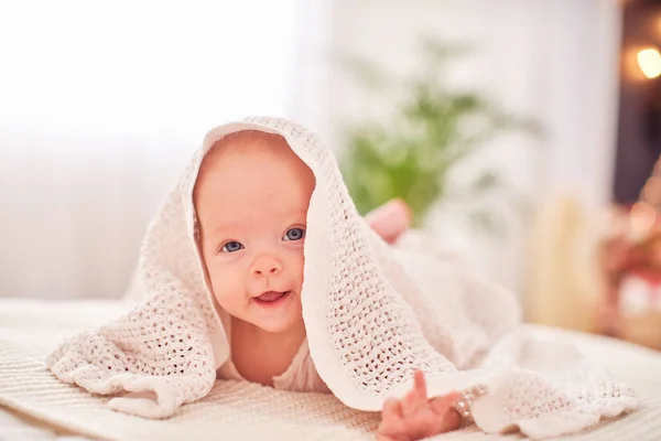 Bebé bajo la toalla. un niño alegre mira hacia fuera de und —  Fotos de Stock