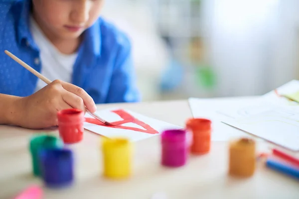 Il bambino disegna con una spazzola vernici ad acquerello su carta il lett — Foto Stock