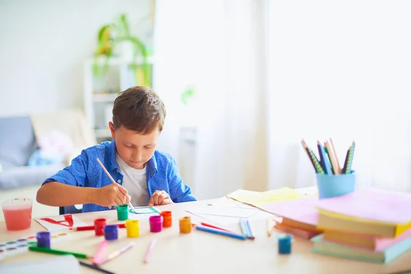 Il bambino disegna con una spazzola vernici ad acquerello su carta il lett — Foto Stock