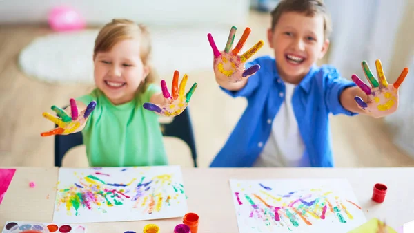 Lustige Kinder zeigen ihren Handflächen die bemalte Farbe. Kreativkurse — Stockfoto