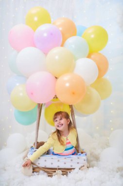 Bebek kız bir bulut üzerinde balon bir sepet yanında oturan 