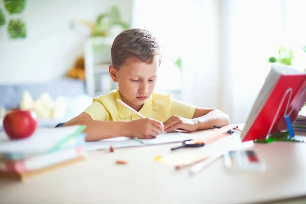 Хлопчик робить домашнє завдання вдома. щаслива дитина за столом з — стокове фото