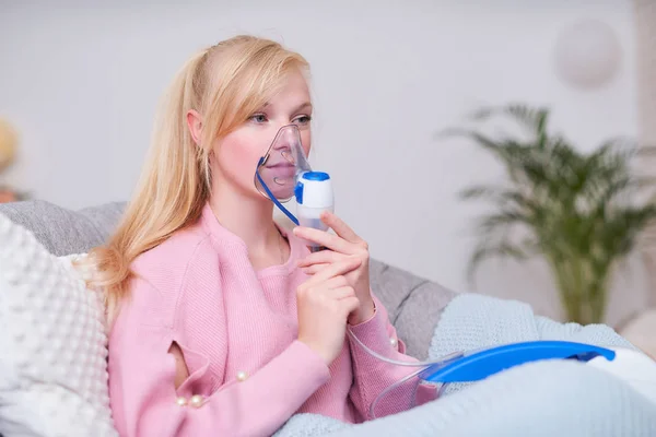 Jonge vrouw inhaleren met een vernevelaar thuis doen — Stockfoto