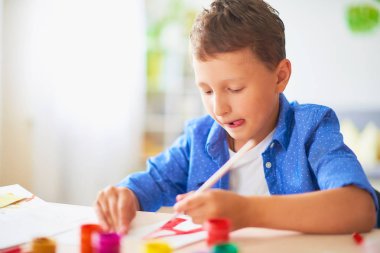 Çocuk kağıt üzerinde bir fırça suluboya boyaları ile çizer lett