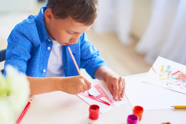 A gyermek felhívja ecsettel akvarell festékek papírra a lett — Stock Fotó